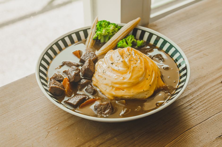 Savor the rich flavors of a beef stew served with creamy mashed potatoes and fresh vegetables in a cozy setting.