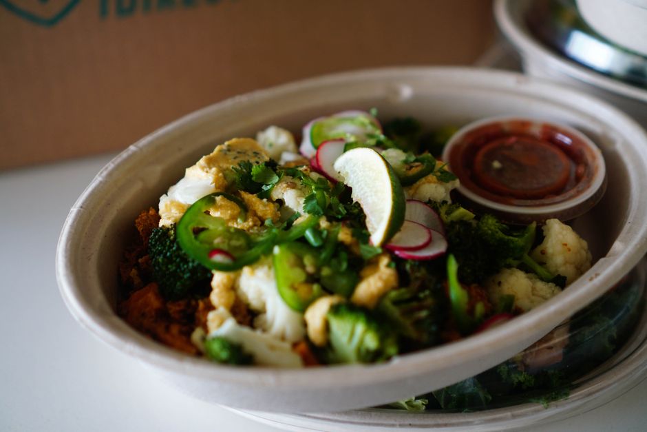 Colorful vegetable salad bowl with broccoli, cauliflower, jalapeno, and lime in eco-friendly packaging.