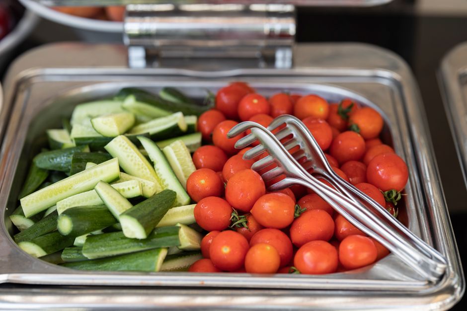Fresh cherry tomatoes and sliced cucumbers in a buffet stainless steel tray, perfect for healthy eating.