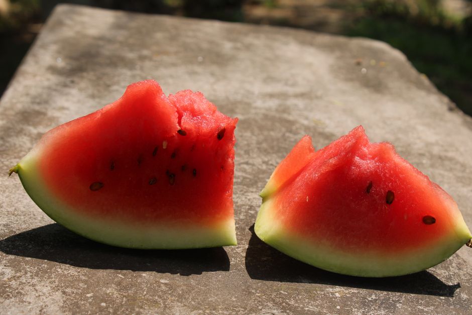 Close-up of juicy watermelon slices with seeds on a stone surface outdoors.