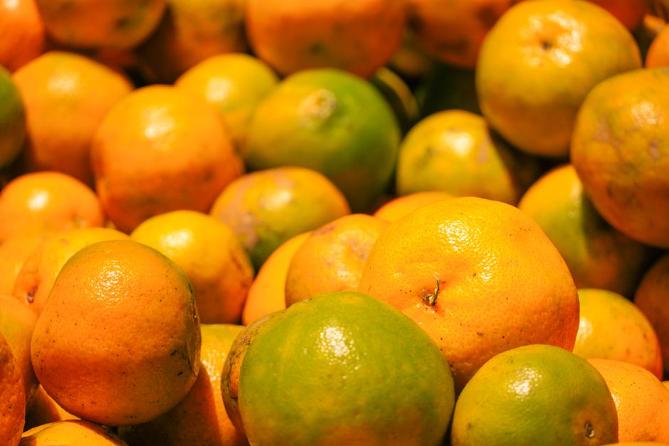 Vibrant display of fresh oranges and limes stacked in Kodaikanal market, Tamil Nadu, India.
