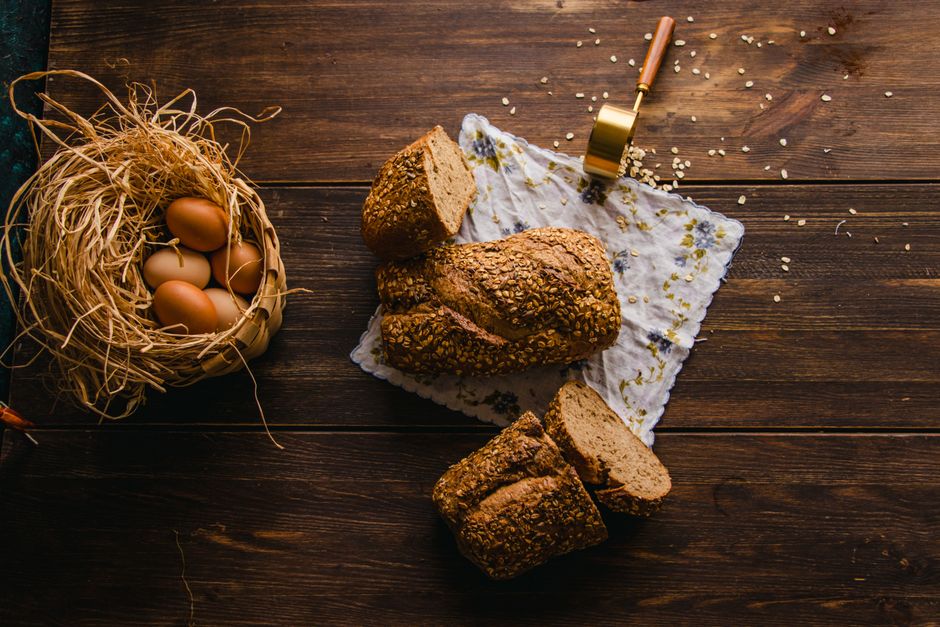Whole grain bread and eggs on a wooden table in a rustic kitchen setting.