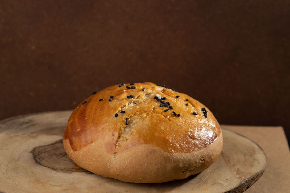 Delicious homemade bread bun topped with black seeds, perfect for any meal.