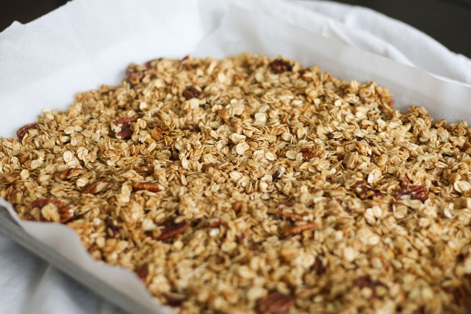 Freshly baked homemade granola with oats and pecans on parchment paper.