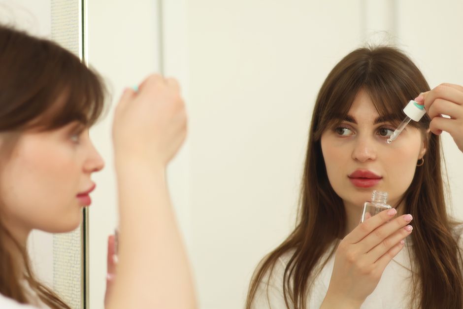 Woman applying skincare in front of a mirror